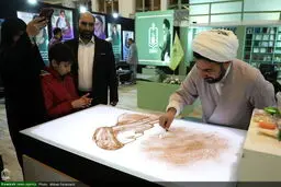 عکسی که خبرگزاری حوزه از نقاشی کشیدن یک روحانی روی شن منتشر کرد 