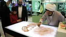 عکسی که خبرگزاری حوزه از نقاشی کشیدن یک روحانی روی شن منتشر کرد 